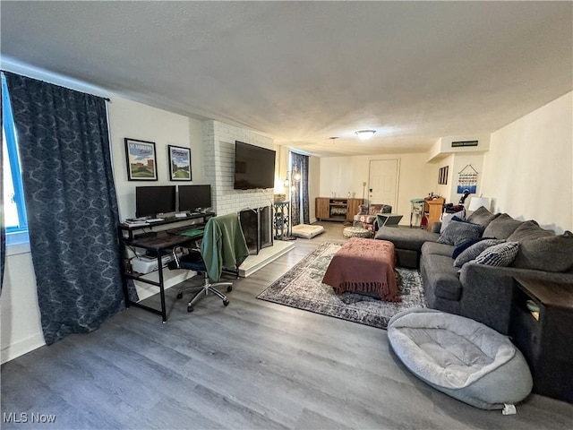 living area with a brick fireplace, visible vents, and wood finished floors