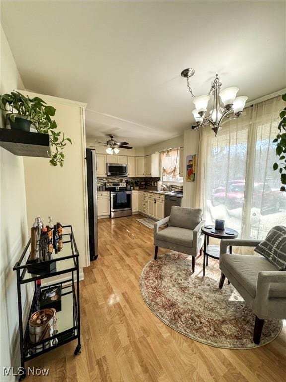 interior space featuring light wood-style flooring and ceiling fan with notable chandelier