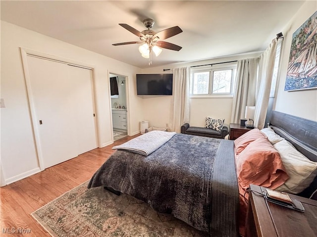 bedroom with baseboards, ceiling fan, wood finished floors, and connected bathroom