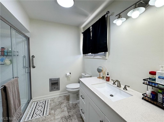 bathroom with heating unit, toilet, a shower stall, vanity, and baseboards