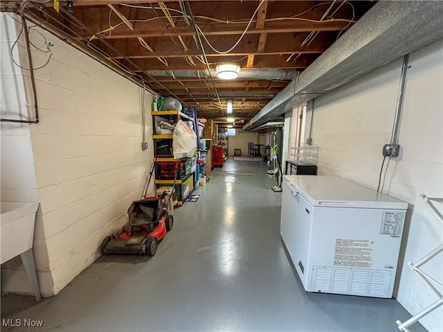 unfinished basement featuring fridge and concrete block wall