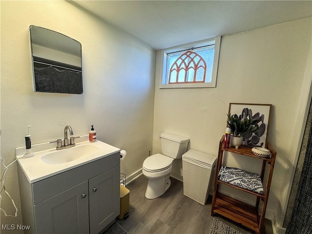 full bathroom with toilet, baseboards, wood finished floors, and vanity