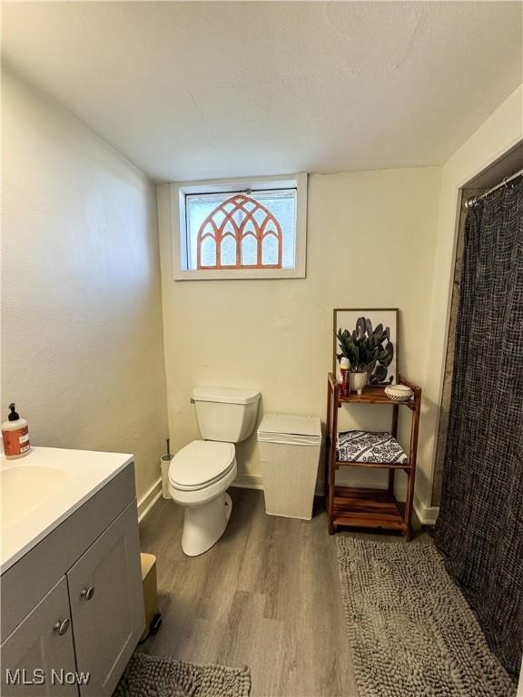 bathroom with baseboards, vanity, toilet, and wood finished floors