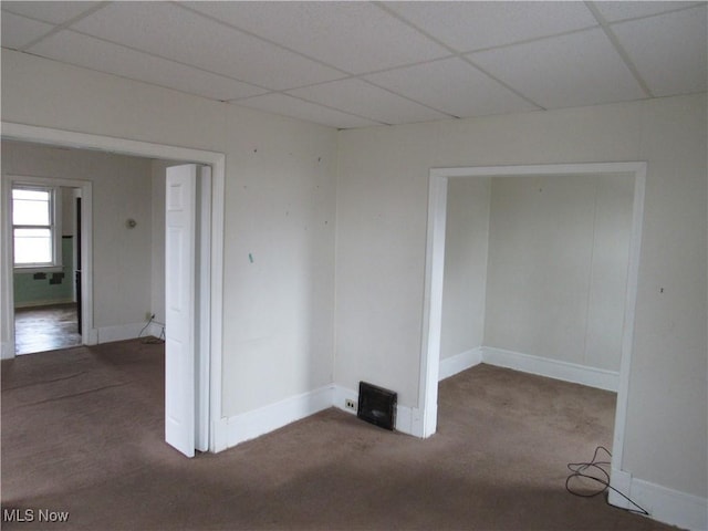 empty room featuring carpet, baseboards, and a drop ceiling