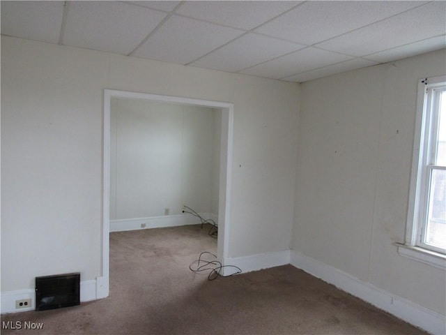 carpeted empty room with a healthy amount of sunlight, a drop ceiling, and baseboards