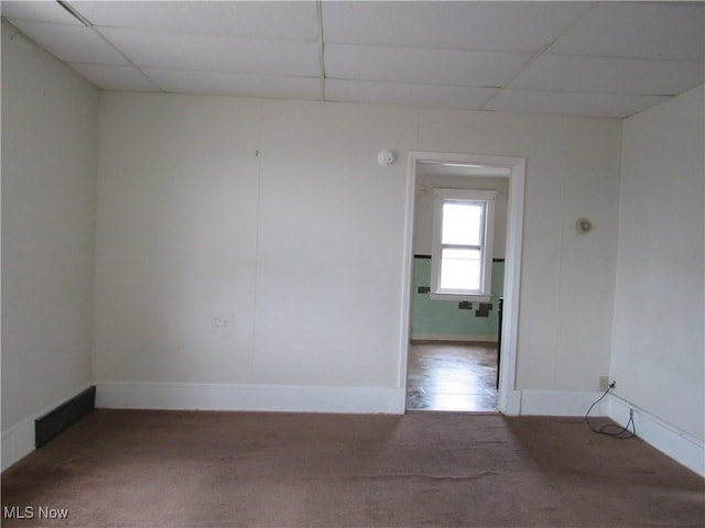 unfurnished room with baseboards and a drop ceiling