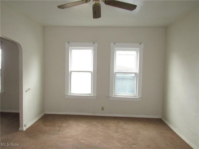 empty room with ceiling fan, baseboards, and light colored carpet