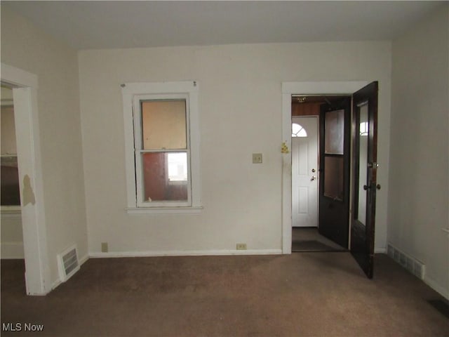 spare room featuring carpet floors, visible vents, and baseboards