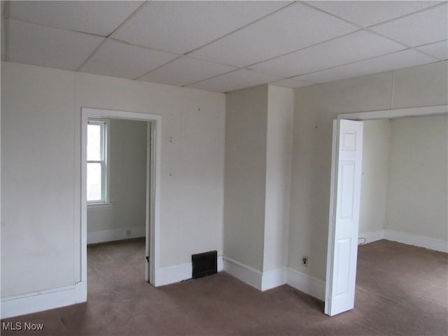 carpeted empty room with a paneled ceiling and baseboards