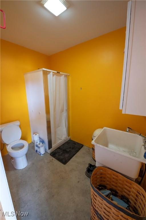 bathroom featuring a sink, a shower stall, and toilet