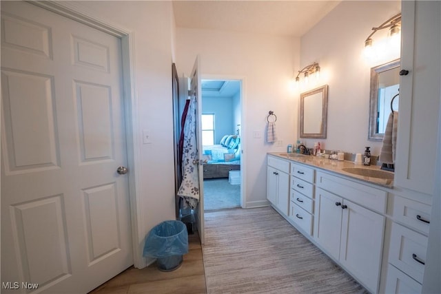 full bath with wood finished floors, double vanity, a sink, and ensuite bathroom