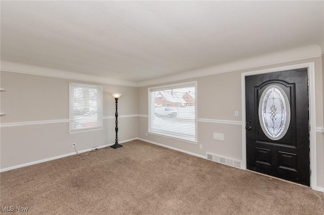 carpeted foyer featuring visible vents and baseboards