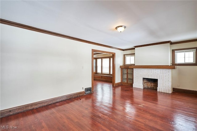 unfurnished living room with a brick fireplace, baseboards, ornamental molding, and wood finished floors