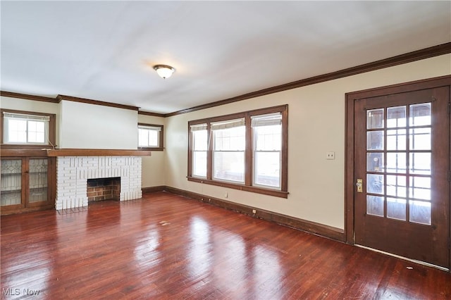 unfurnished living room featuring a brick fireplace, crown molding, baseboards, and wood finished floors