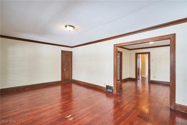 spare room featuring crown molding, baseboards, and wood finished floors