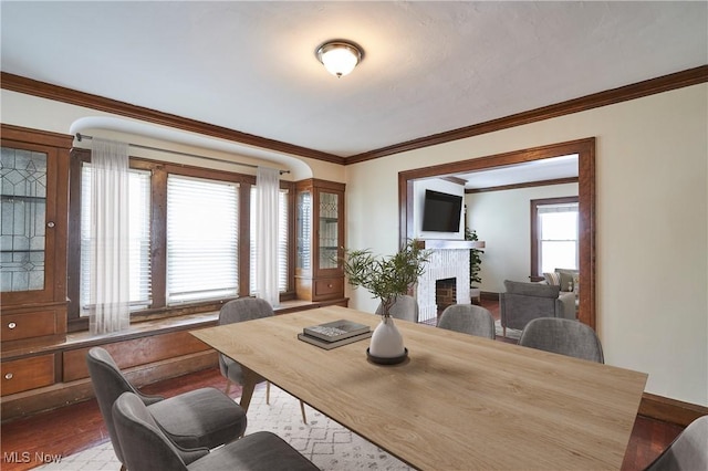 dining room featuring dark wood-style floors, ornamental molding, and a fireplace