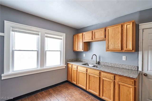 kitchen featuring brown cabinets, baseboards, dark wood-style flooring, and a sink