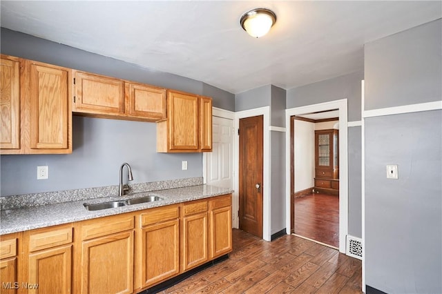 kitchen with dark wood finished floors, visible vents, a sink, and baseboards