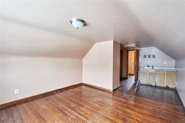 additional living space featuring lofted ceiling, visible vents, baseboards, and hardwood / wood-style flooring