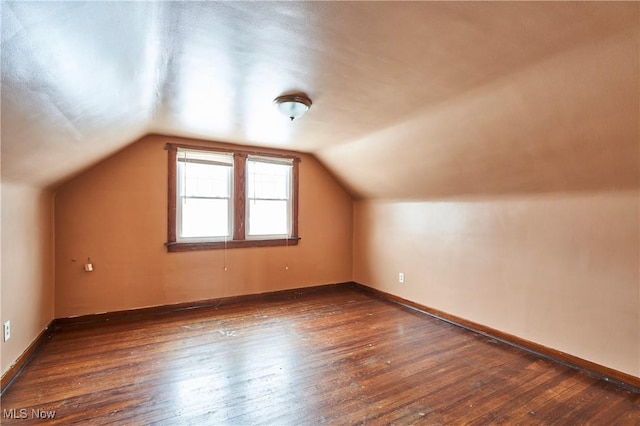 additional living space with vaulted ceiling, wood-type flooring, and baseboards