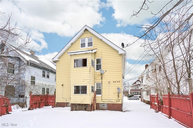 snow covered back of property featuring crawl space and fence