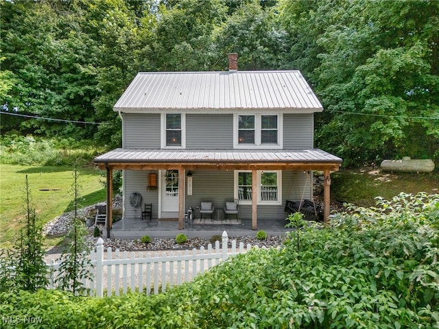 country-style home with metal roof, a chimney, and a porch