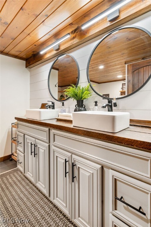 8950 County Road 292, Millersburg, OH 44654 - full bath featuring double vanity, wooden ceiling, a sink, and tile patterned floors