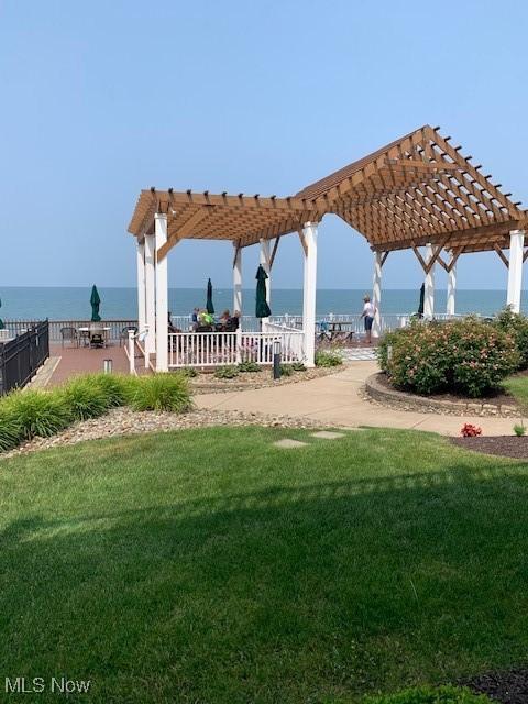 surrounding community featuring a lawn, a water view, and a pergola