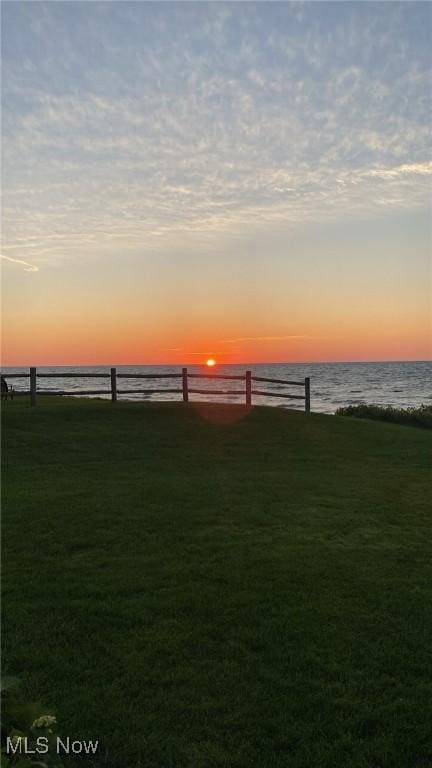 yard at dusk featuring a water view