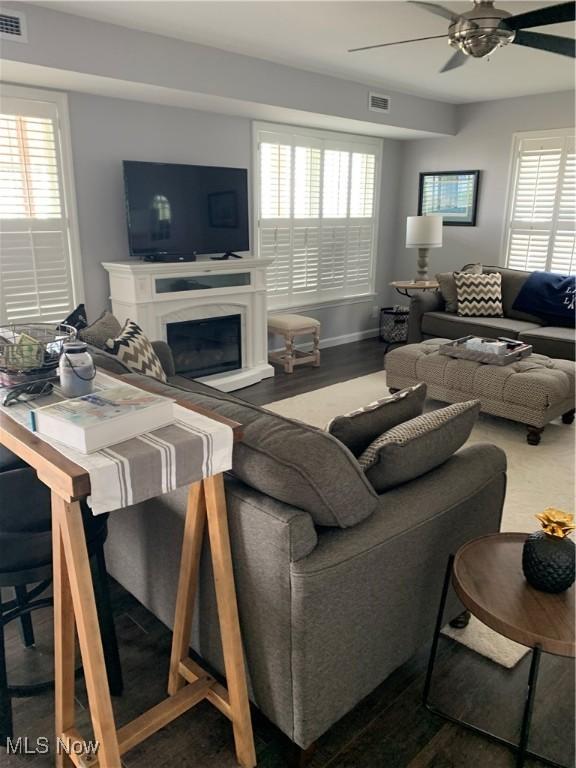 living room with ceiling fan, a fireplace, wood finished floors, and visible vents