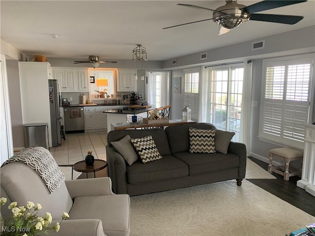 living area featuring a ceiling fan, a healthy amount of sunlight, visible vents, and light tile patterned floors