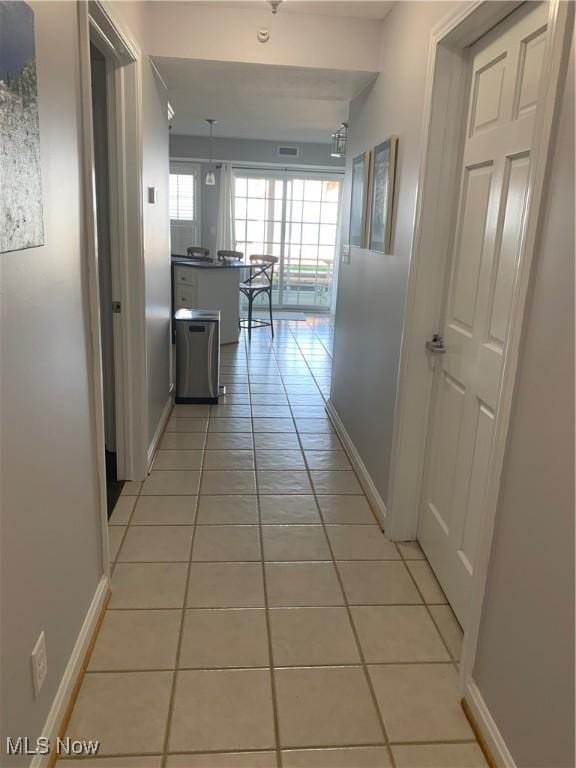 hall with baseboards and light tile patterned flooring