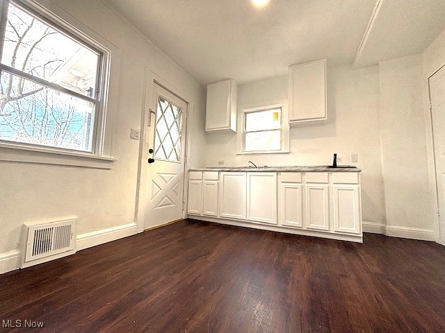 kitchen featuring white cabinets, baseboards, visible vents, and dark wood finished floors