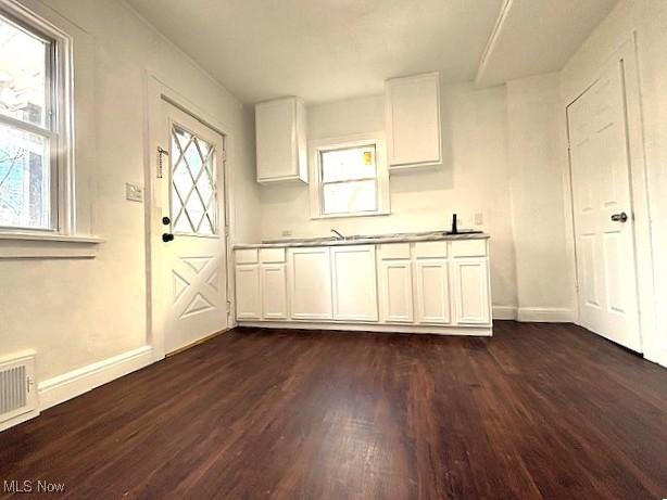 kitchen with dark wood-style flooring, white cabinetry, visible vents, and baseboards