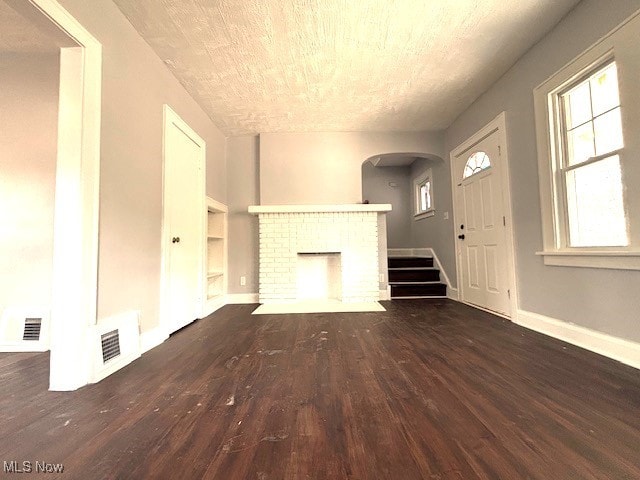 unfurnished living room featuring baseboards, a fireplace, visible vents, and wood finished floors