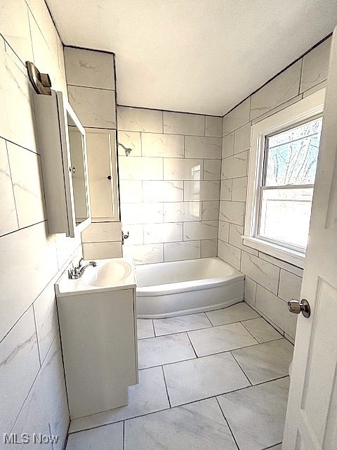 full bath featuring a textured ceiling, a bathing tub, and vanity