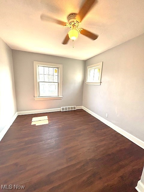 spare room featuring dark wood finished floors, visible vents, a ceiling fan, a textured ceiling, and baseboards