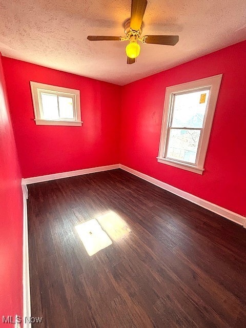 unfurnished room with baseboards, a textured ceiling, wood finished floors, and a healthy amount of sunlight