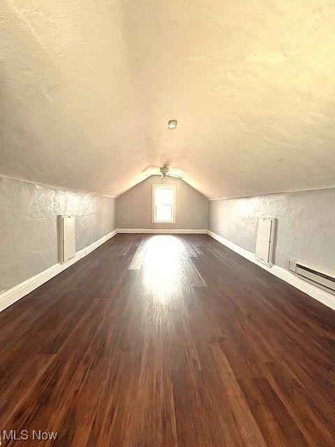 additional living space featuring lofted ceiling, a textured ceiling, baseboards, and dark wood-type flooring