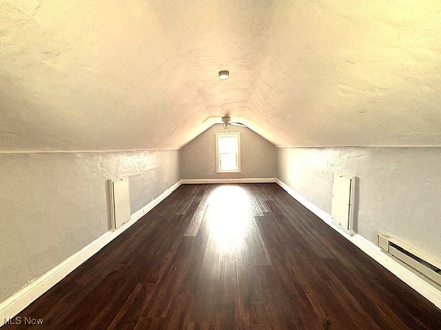 bonus room with a textured ceiling, lofted ceiling, a baseboard heating unit, wood finished floors, and baseboards