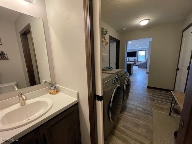 bathroom featuring a textured ceiling, vanity, wood finished floors, and independent washer and dryer