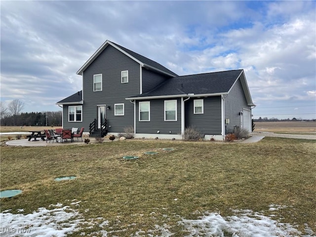 rear view of property with a garage, entry steps, a patio, and a lawn