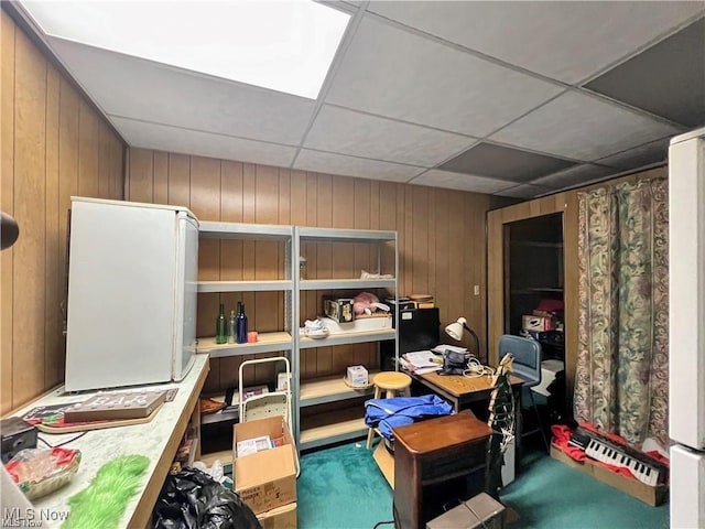 interior space featuring wood walls, a drop ceiling, and carpet flooring