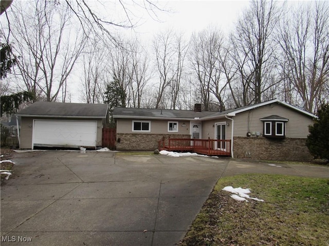 ranch-style home with a garage, driveway, a chimney, a deck, and brick siding