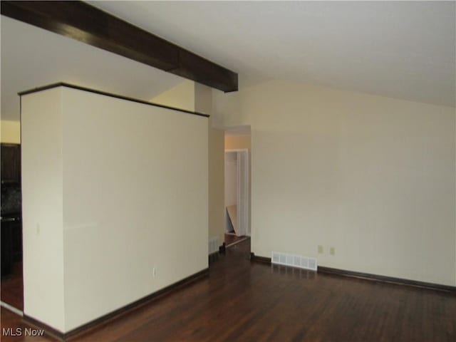 spare room with visible vents, vaulted ceiling with beams, baseboards, and wood finished floors