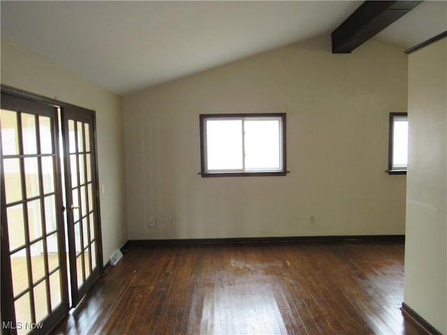 empty room featuring lofted ceiling with beams, a wealth of natural light, hardwood / wood-style flooring, and baseboards