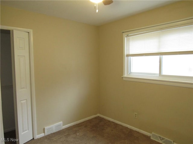 empty room with carpet, visible vents, ceiling fan, and baseboards