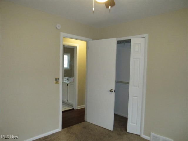 unfurnished bedroom featuring a sink, carpet flooring, visible vents, baseboards, and a closet