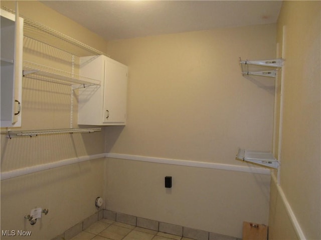 laundry room with light tile patterned floors, baseboards, cabinet space, and hookup for a gas dryer