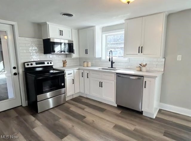 kitchen with tasteful backsplash, dark wood-style flooring, stainless steel appliances, white cabinetry, and a sink